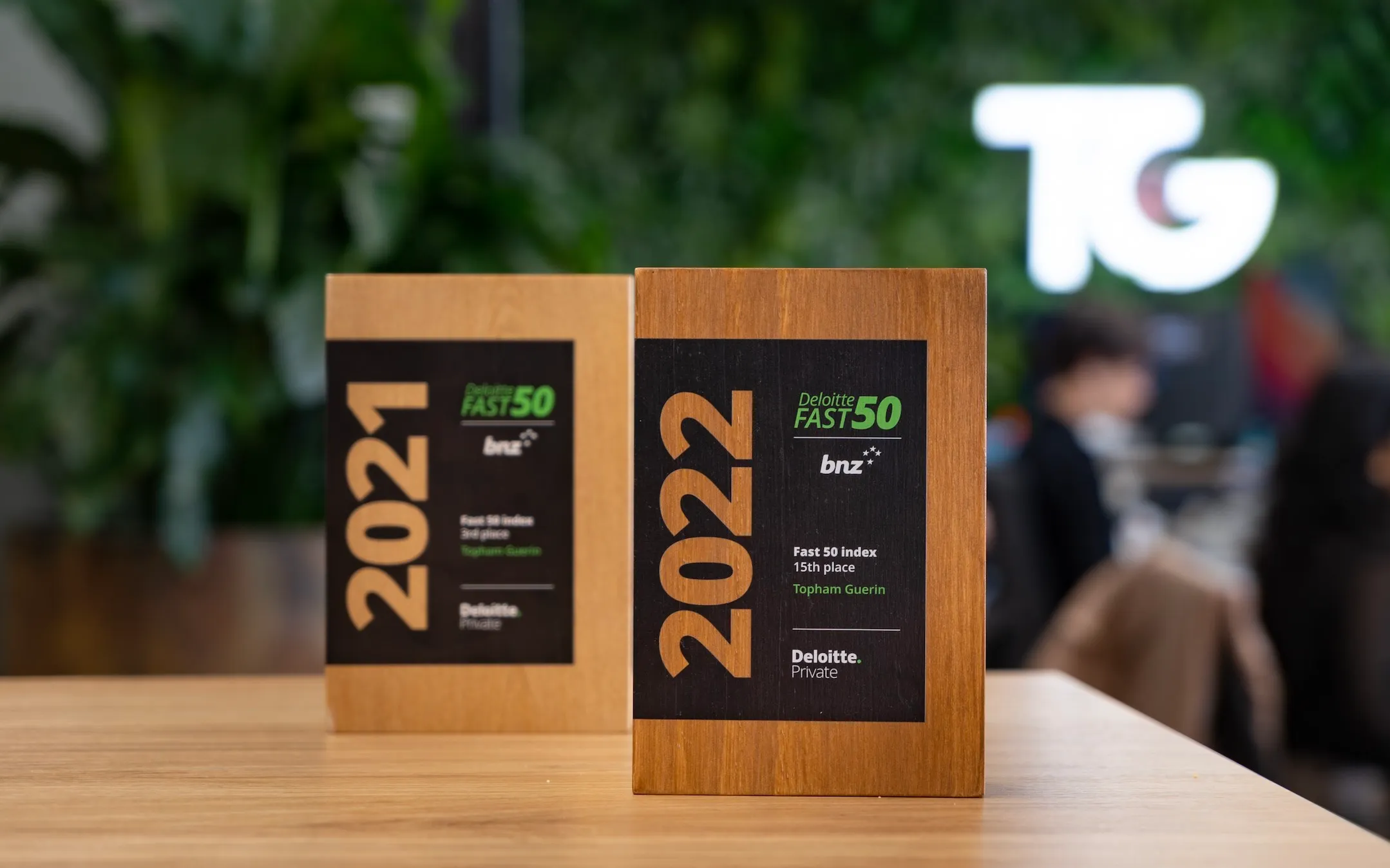 Topham Guerin’s 2021 and 2022 Deloitte Fast 50 award trophies on a table in front of the TG logo.