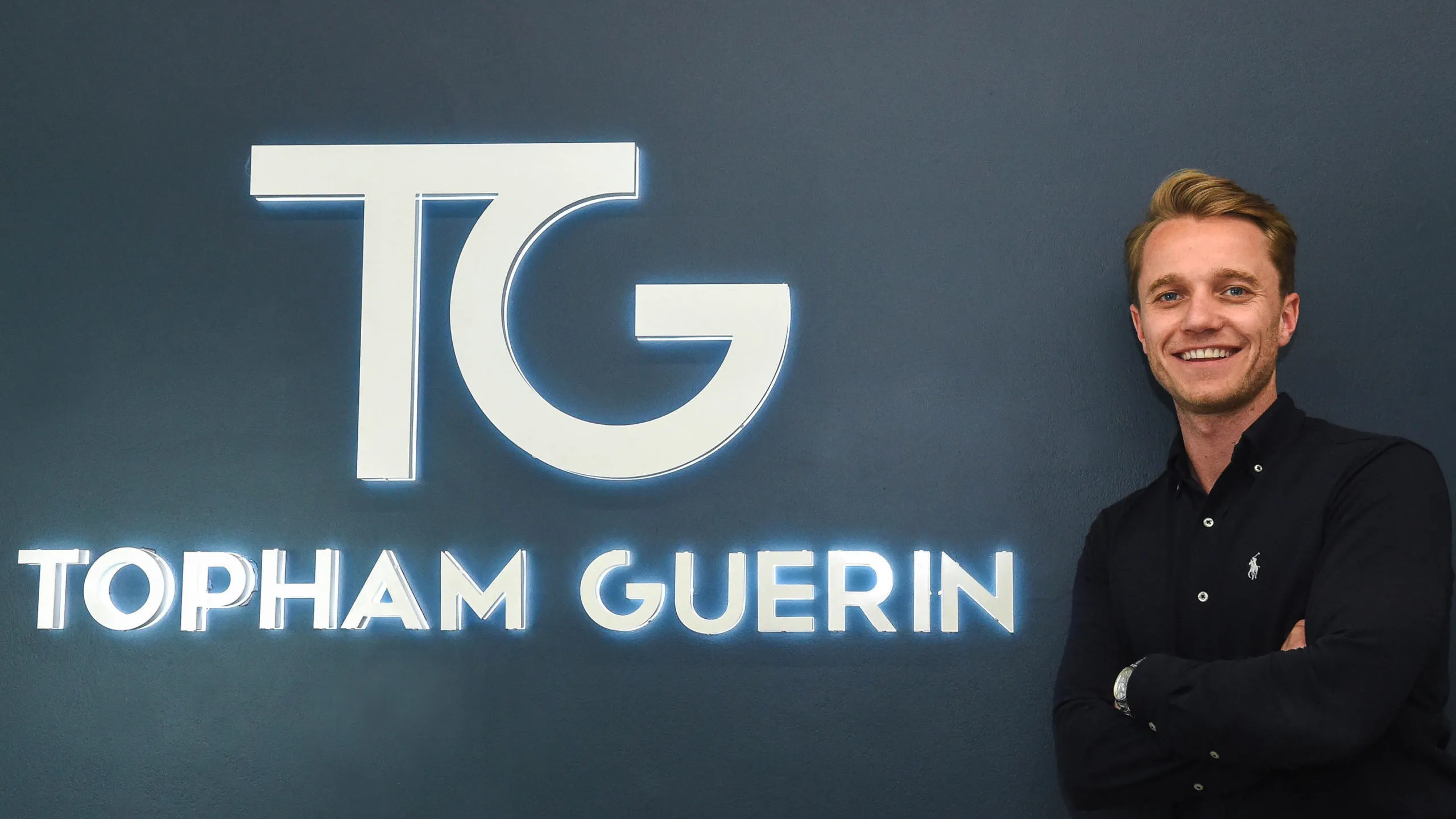 Topham Guerin’s APAC managing director Sam Newton beside the illuminated TG wall logo.